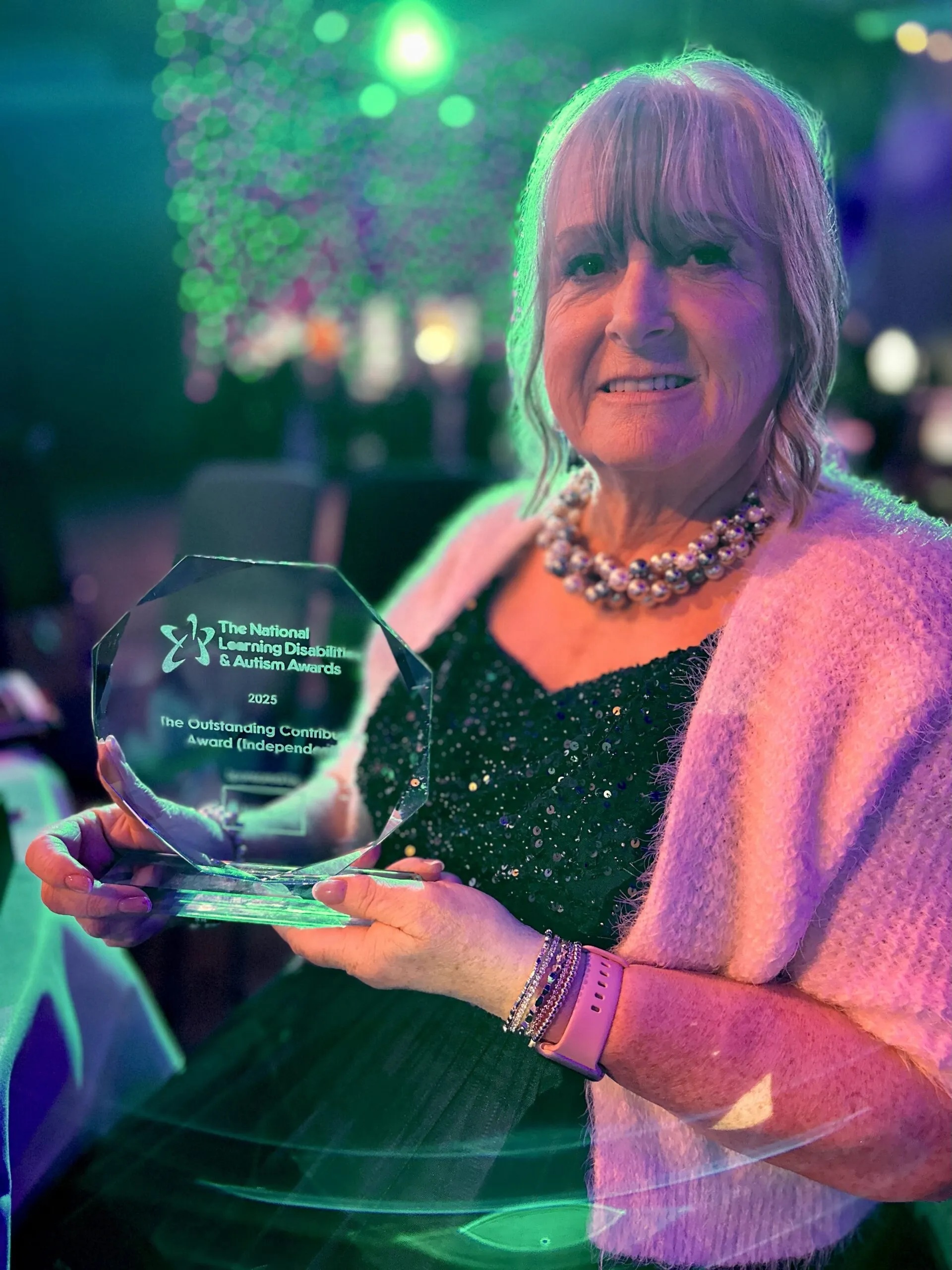 Laurie holding her Outstanding Contribution Award (Independent) at the 2025 National Learning Disabilities & Autism Awards